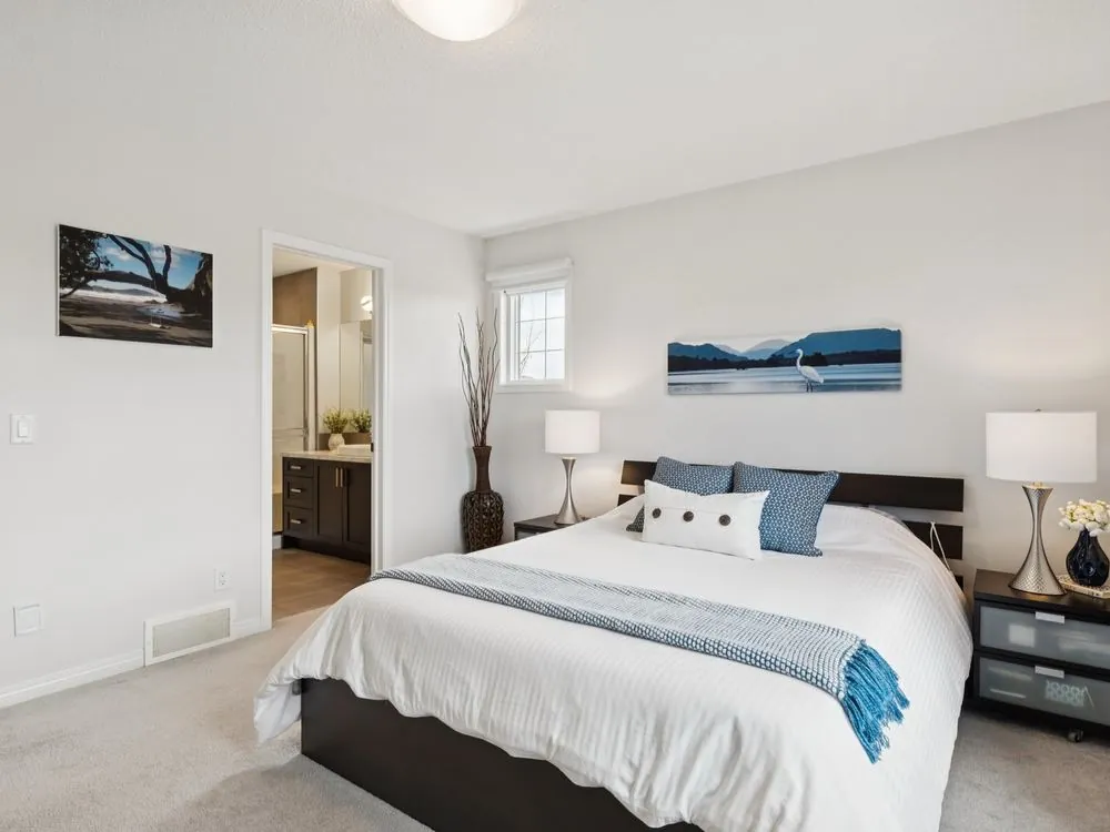 The same bedroom after staging and professional photography: layered bedding, matching lamps, wall art and bright, even light